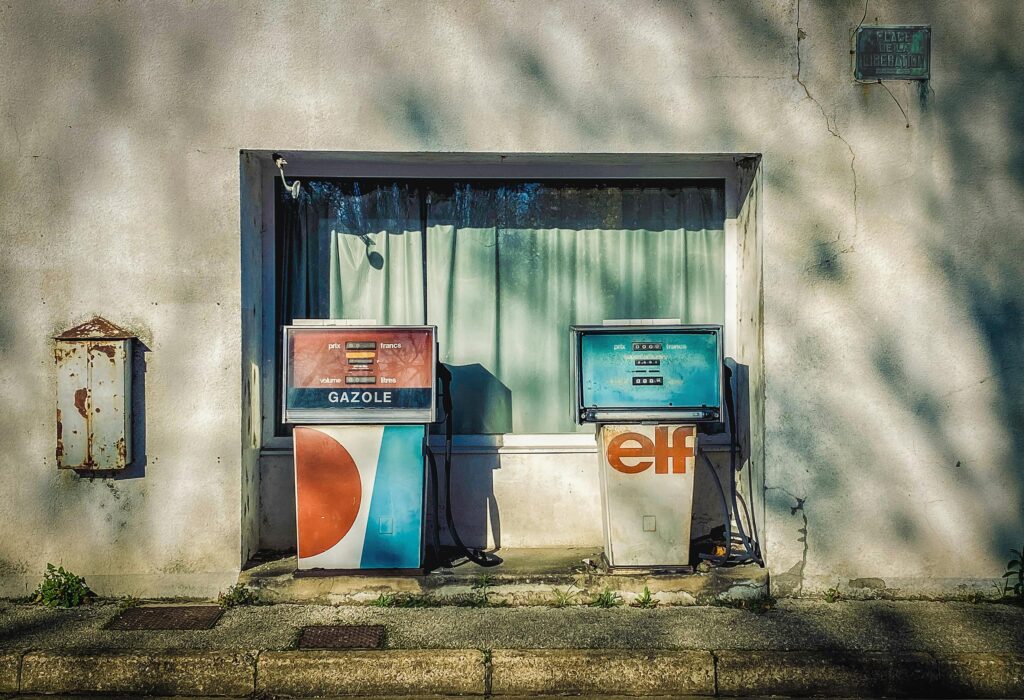Old gasoline pumps in Troo, France, showcasing nostalgic design against a vintage building facade.
