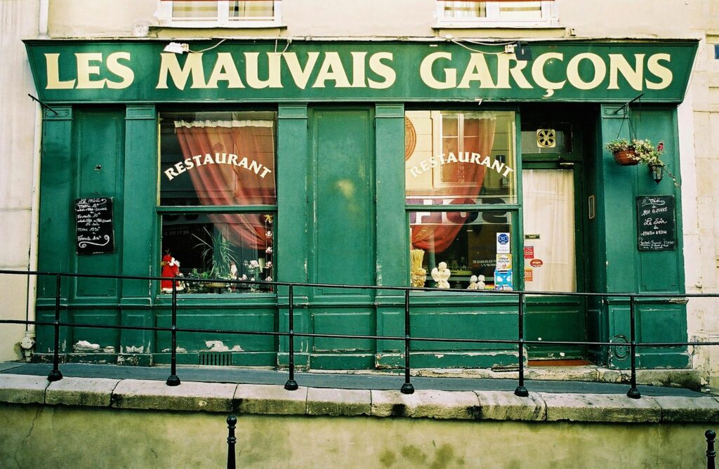 Front view of the Les Mauvais Garçons restaurant in Paris showcasing its green facade.
